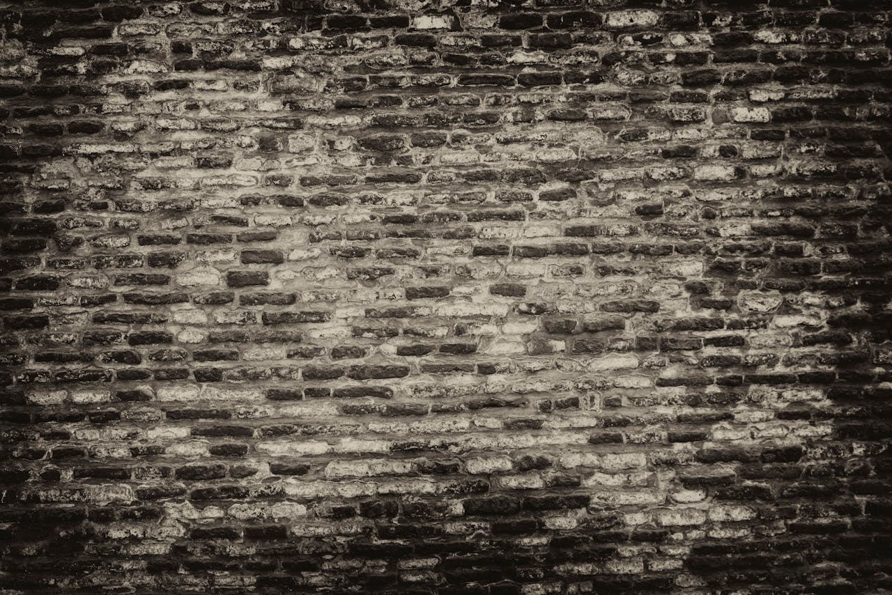 Grayscale textured brick wall background with rough surface.